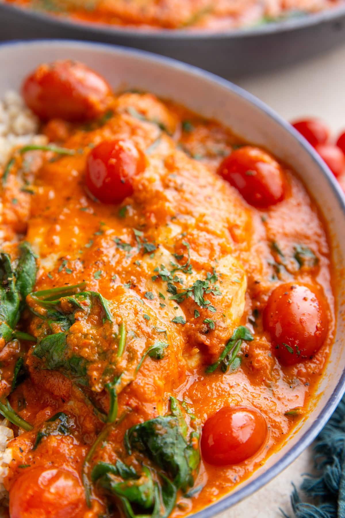 Bowl with creamy red pepper chicken and rice with cherry tomatoes and spinach.