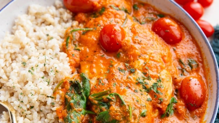 Bowl full of creamy red bell pepper chicken with rice.