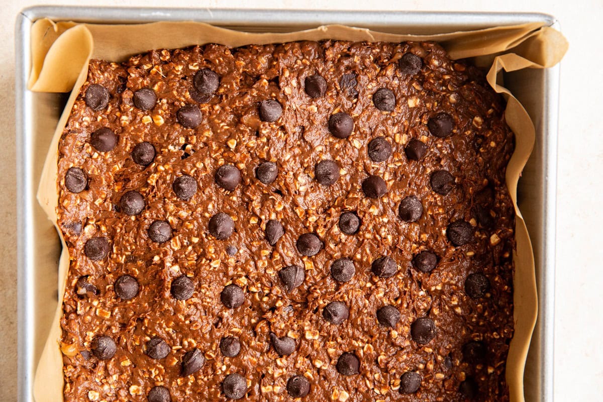 Chocolate breakfast bar batter in a baking dish with chocolate chips on top, ready to go into the oven.