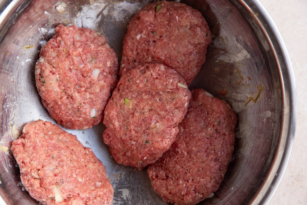 Salisbury steak patties in a mixing bowl.