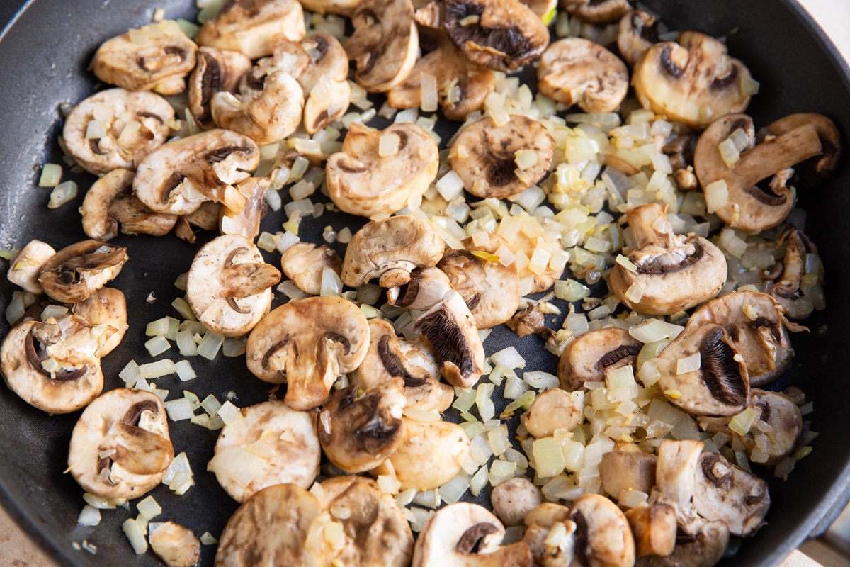 Onions, garlic, and mushrooms cooking in a skillet.