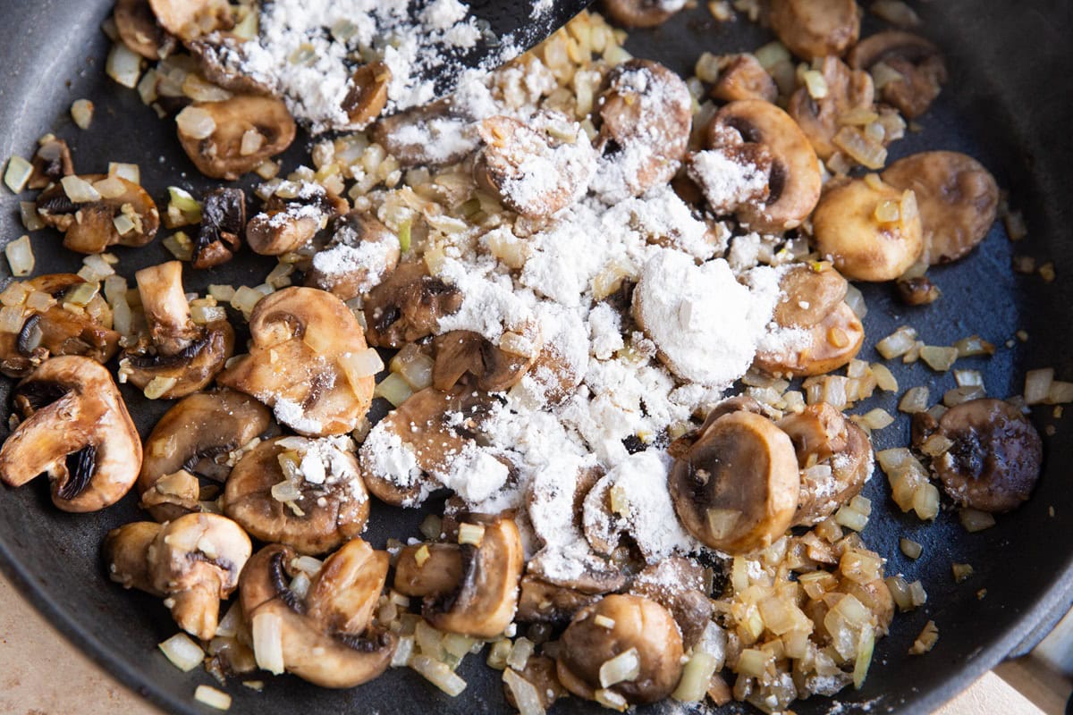 Flour sprinkled over onions, mushrooms, and garlic.