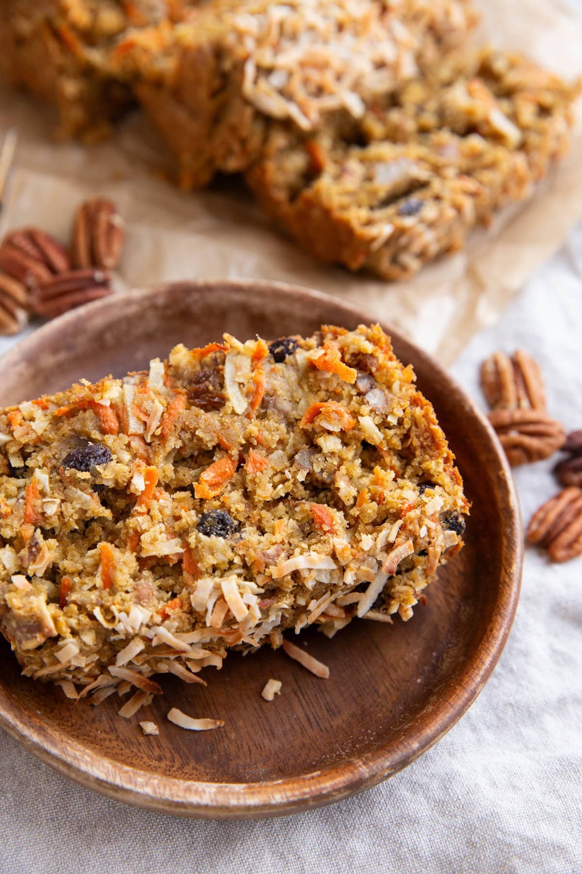 Sliced carrot cake bread in a plate and more carrot bread in the background.