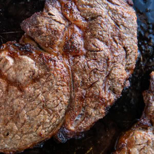 Ribeye steaks fresh out of the oven on a baking sheet.