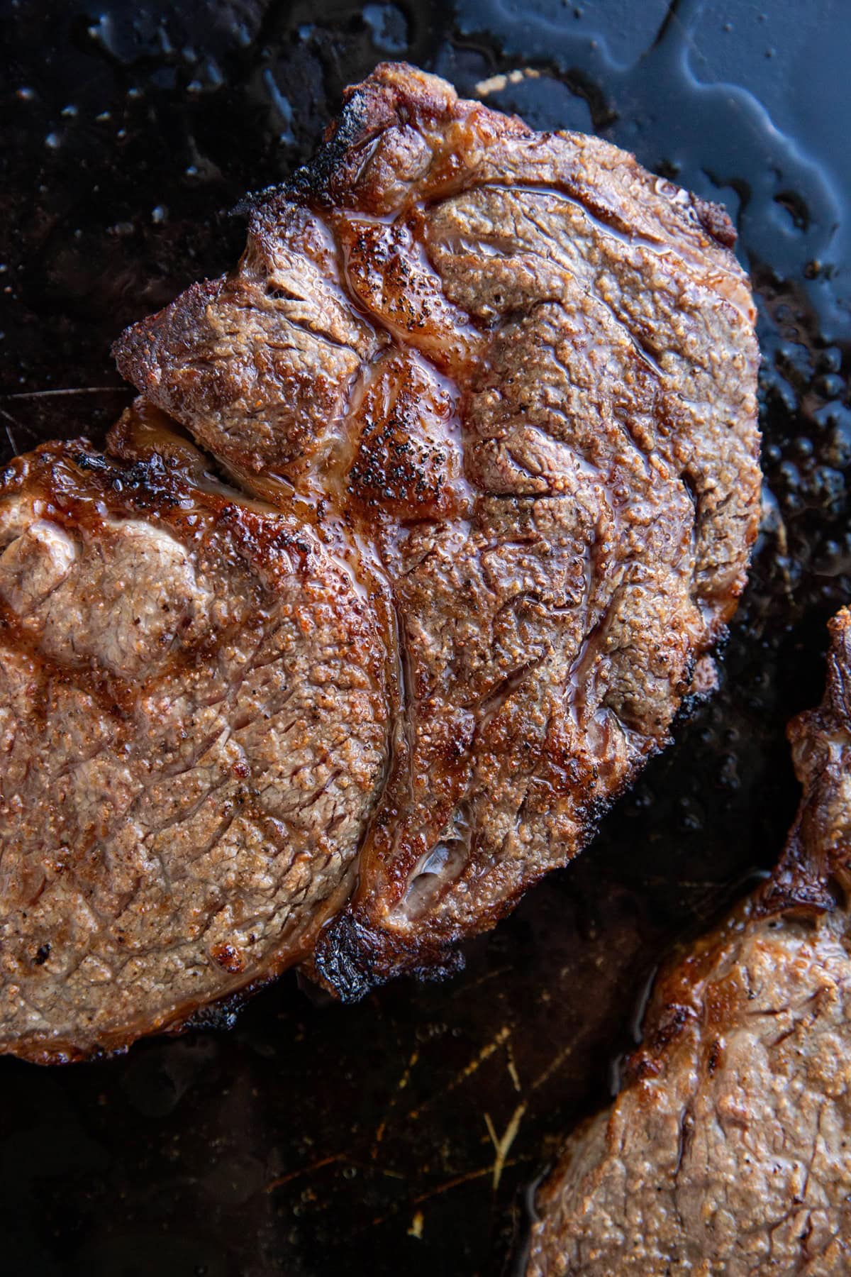 Ribeye steaks fresh out of the oven on a baking sheet.