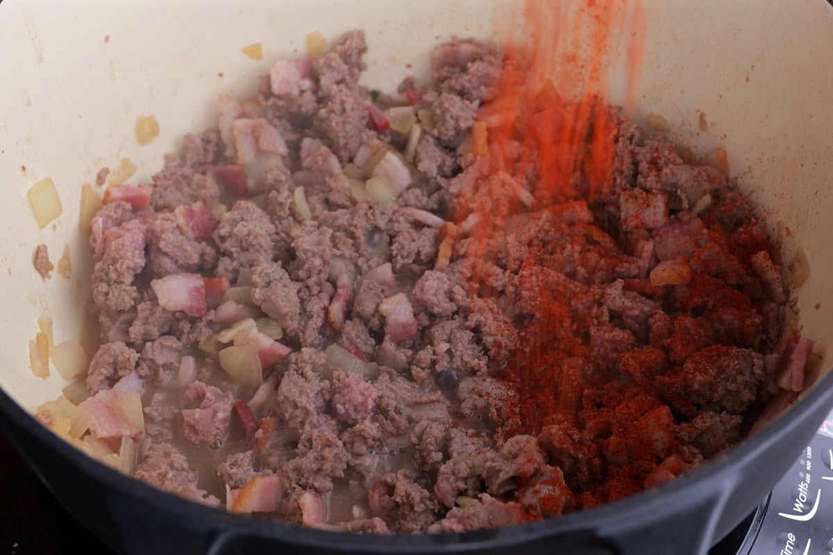 Italian sausage, bacon, onion and seasonings cooking in a large pot