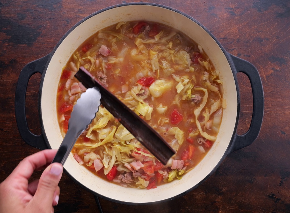 Tongs taking cinnamon stick out of the soup pot.