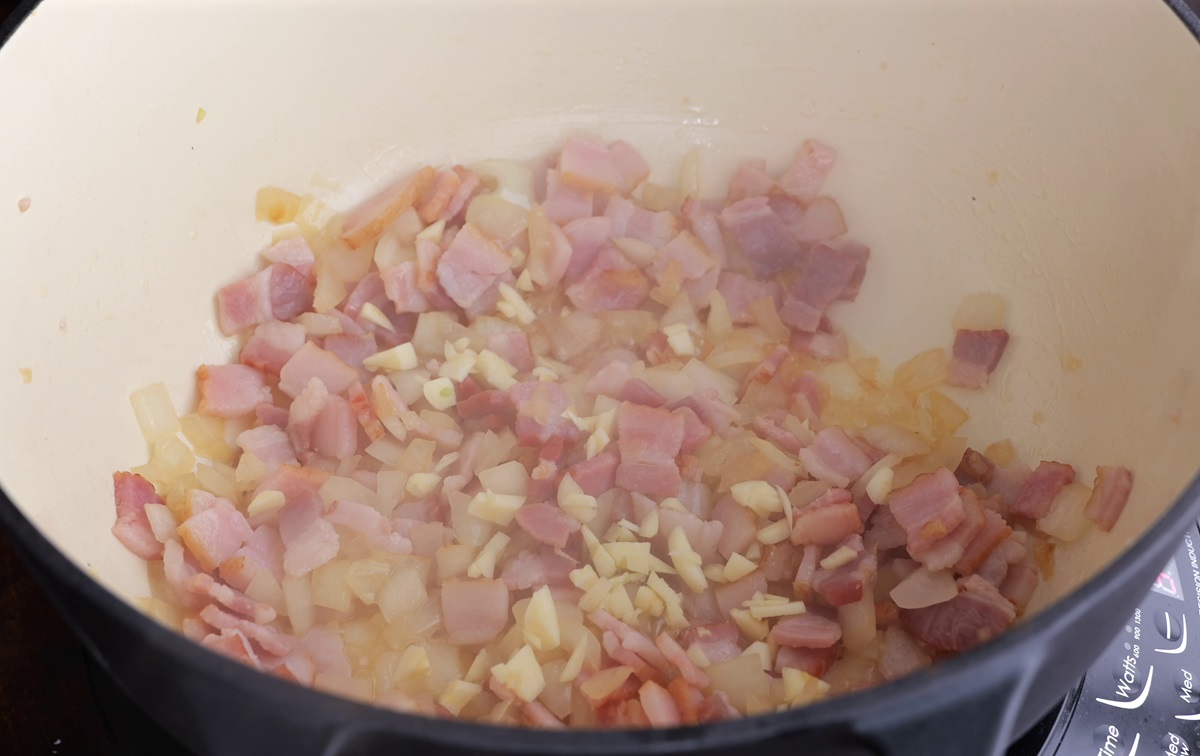Onions, garlic, and bacon cooking in a large pot.
