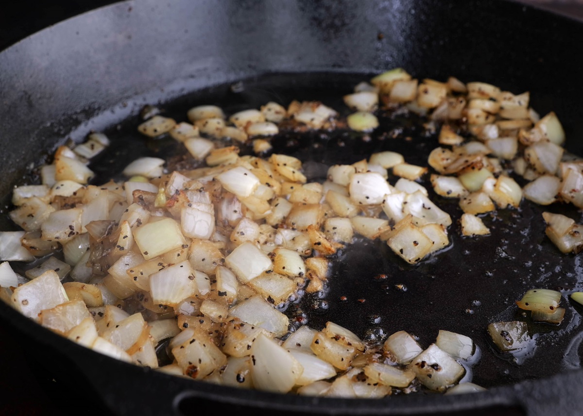 Onions sautéing in a cast iron skillet.