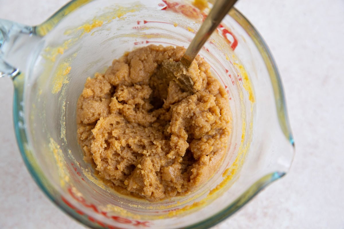 Peanut butter cookie dough in a measuring cup.