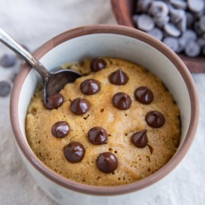 Peanut butter cookie in a mug with chocolate chips on top.