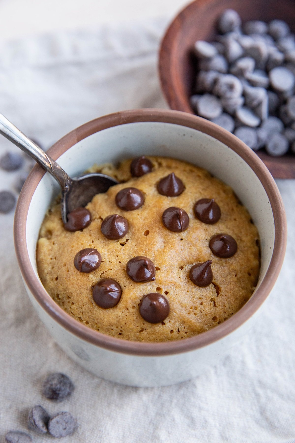 Peanut butter cookie in a mug with chocolate chips on top.