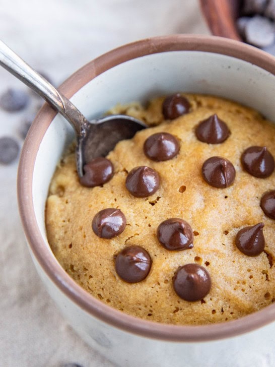 Peanut butter cookie in a small ramekin with chocolate chips on top, ready to eat.