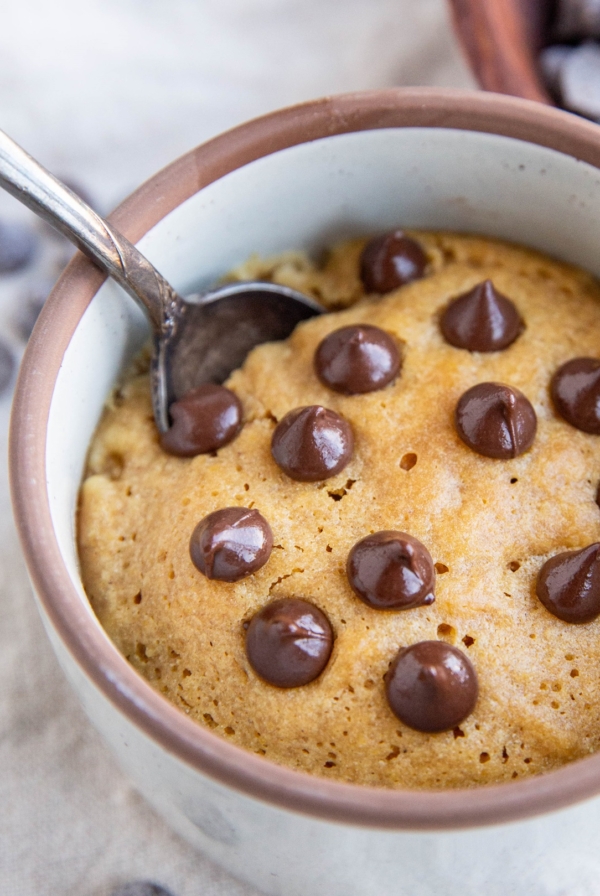 Peanut butter cookie in a small ramekin with chocolate chips on top, ready to eat.