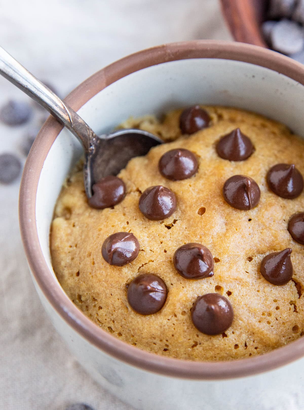 Peanut butter cookie in a small ramekin with chocolate chips on top, ready to eat.