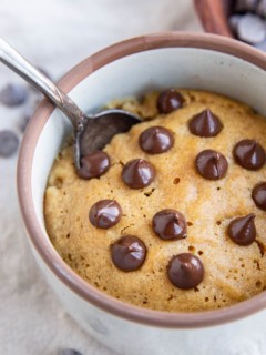Close up image of a peanut butter cookie in a mug with chocolate chips