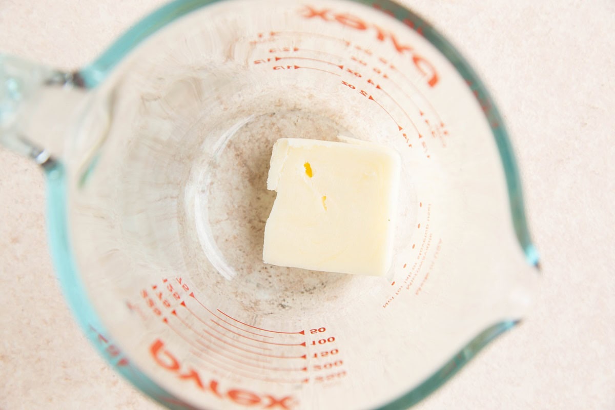 one tablespoon of butter in a measuring cup, ready to be melted.