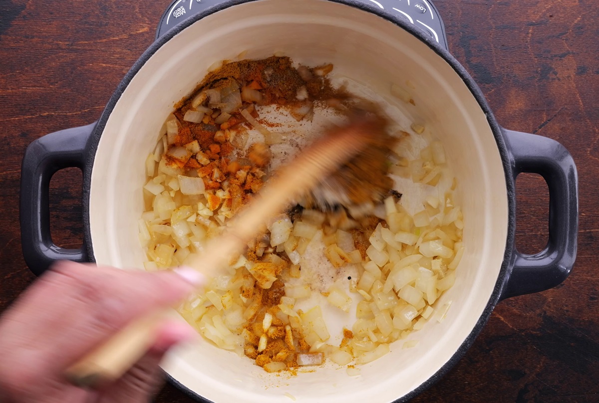 Sautéing spices with onion in a large pot.