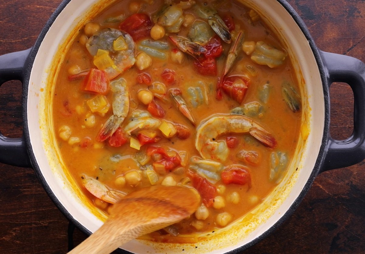 Raw shrimp and garbanzo beans in a large pot, cooking.