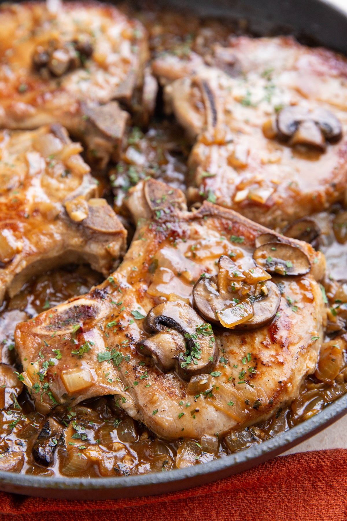 Seared pork chops in a skillet with mushroom gravy, ready to serve.