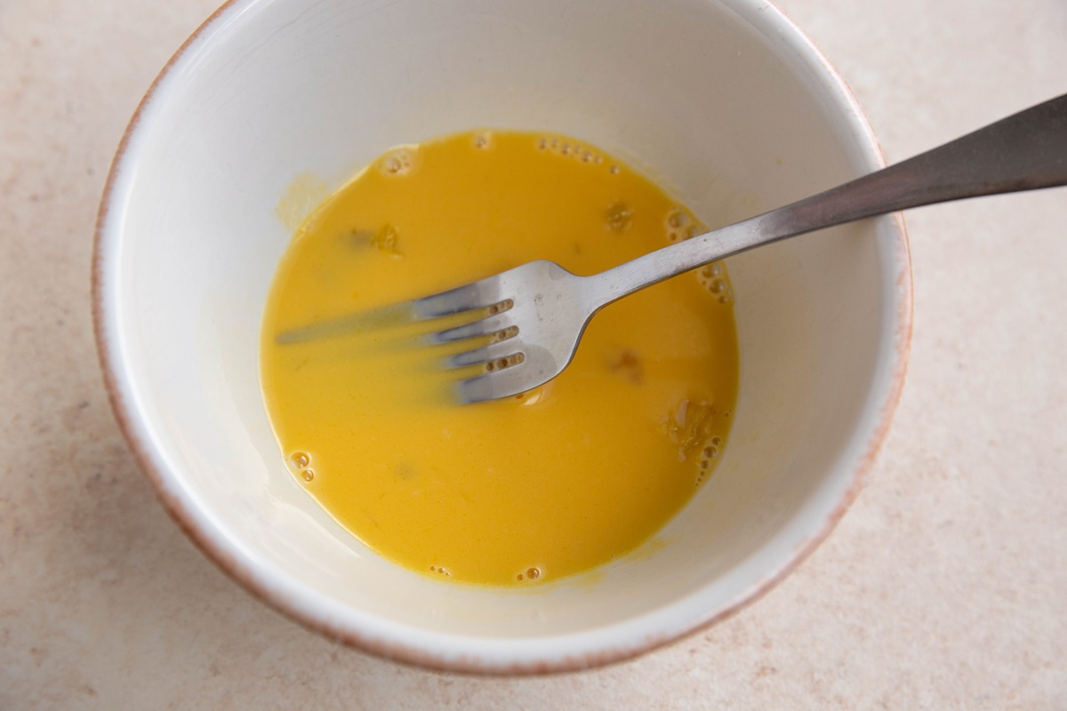 Egg yolks mixed with broth in a bowl to temper the yolks.