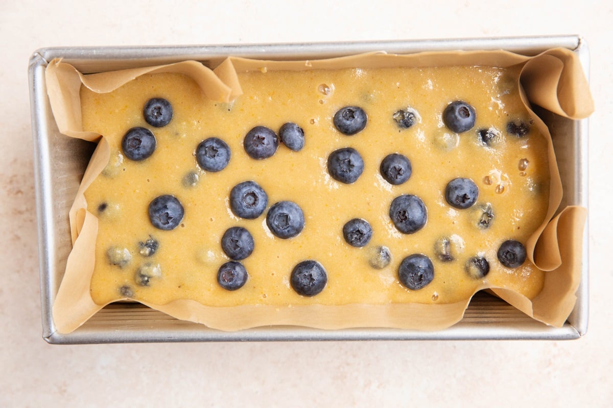 Batter in a loaf pan with blueberry bread.
