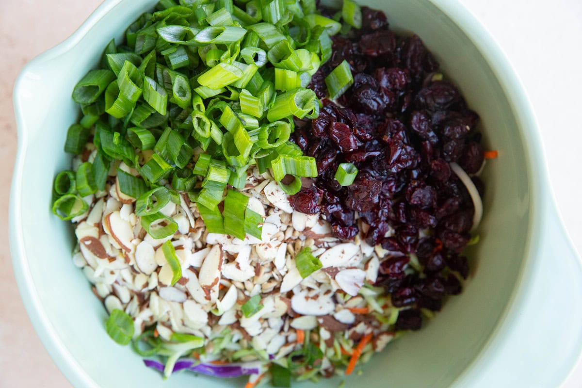 Mixing bowl full of broccoli slaw ingredients.