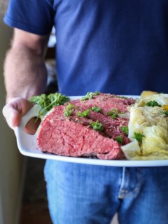 Man holding a platter of corned beef and cabbage