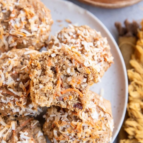 White plate of carrot cake muffins with one sliced in half so you can see the inside.
