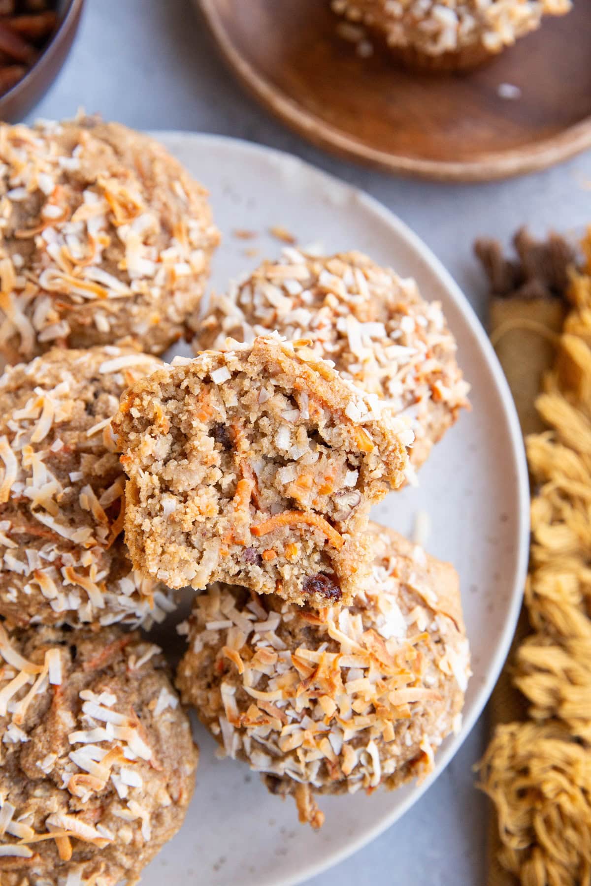 White plate of carrot cake muffins with one sliced in half so you can see the inside.