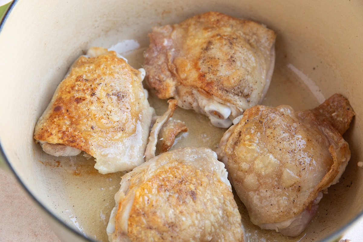 Chicken thighs browning in a large pot.