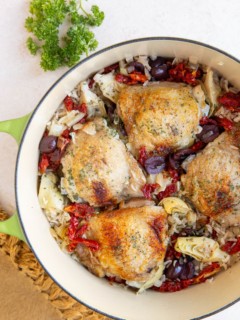 Large pot of chicken and rice with olives, tomatoes, and artichoke hearts.