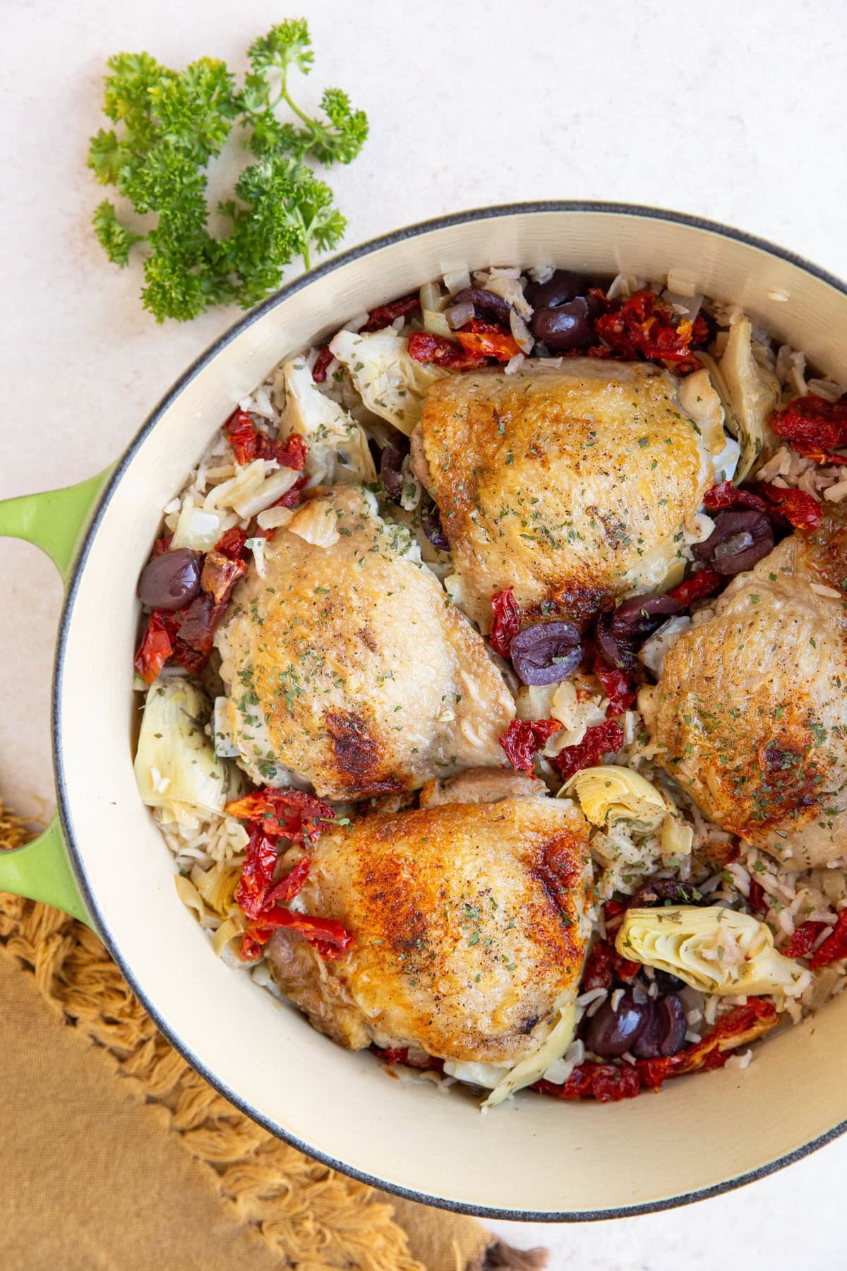 Large pot of chicken and rice with olives, tomatoes, and artichoke hearts.