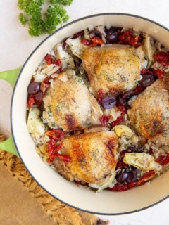Pot of Mediterranean chicken with rice and sun-dried tomatoes, kalamata olives, and artichoke hearts.
