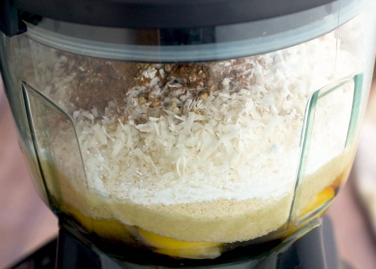 Food processor with carrot cake ingredients inside.