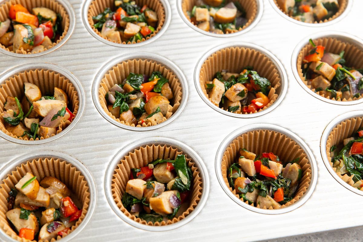 Muffin tray with sausage and vegetables to make egg cups.