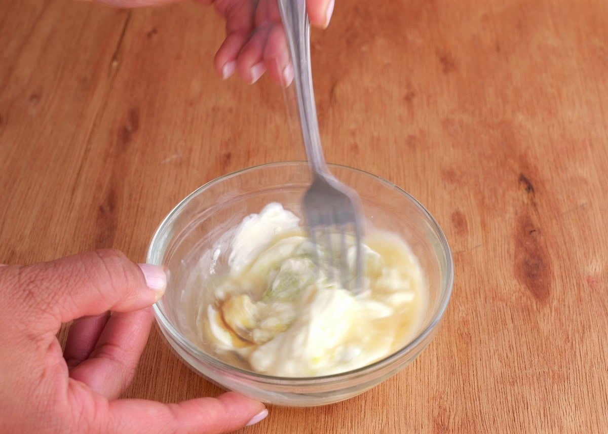 Hands stirring up a bowl of wasabi sauce.