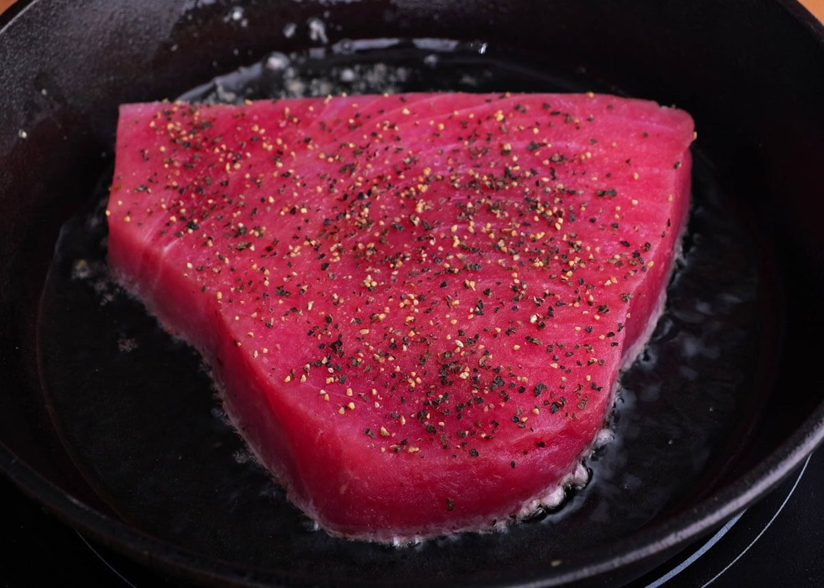 Ahi steak searing in a cast iron skillet.