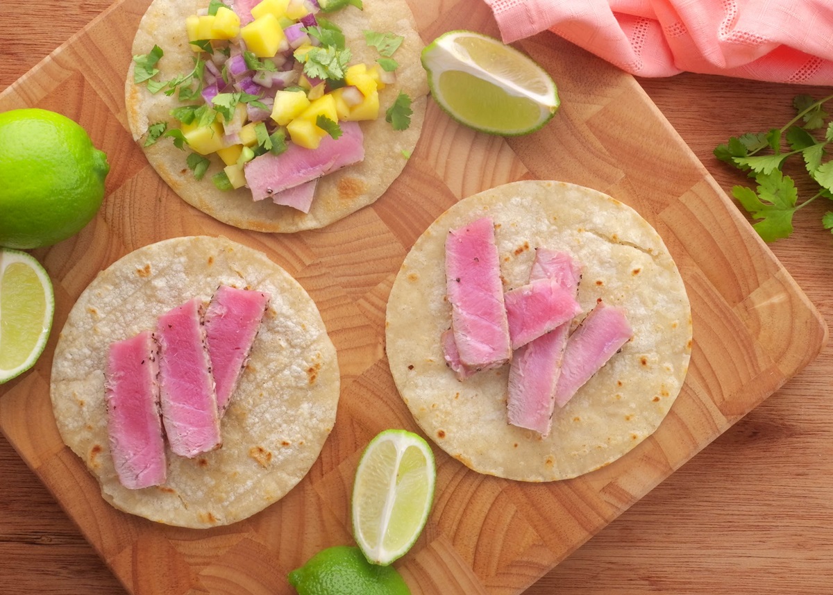 Ahi tacos being compiled on a wooden cutting board.