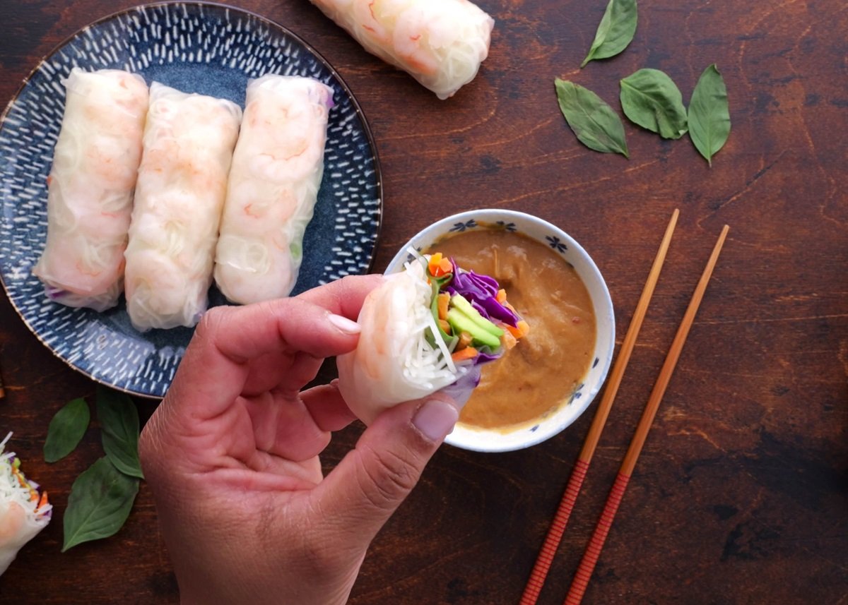 Hand holding a spring roll, exposing the inside.