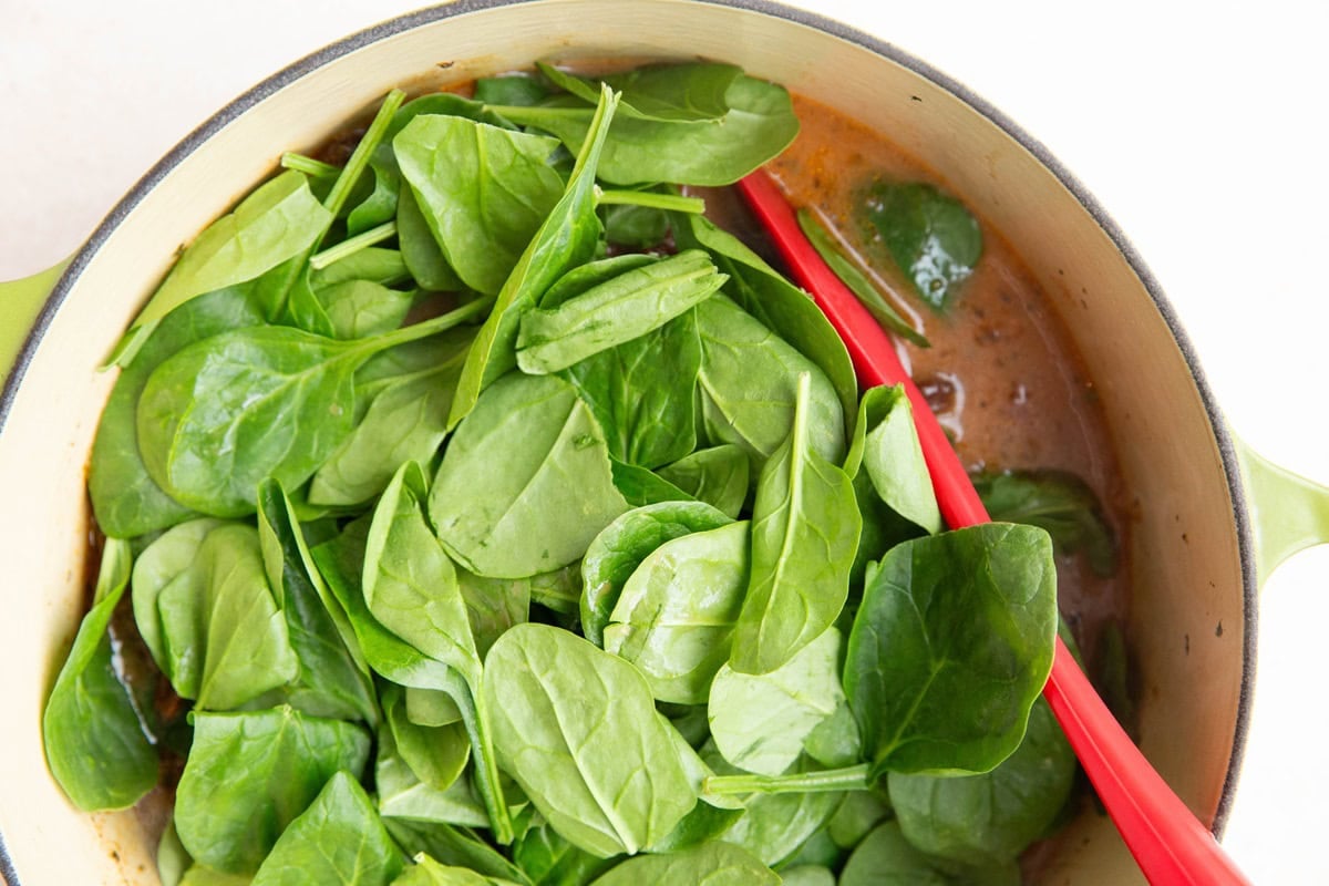 Spinach on top of soup, ready to be cooked into the soup.