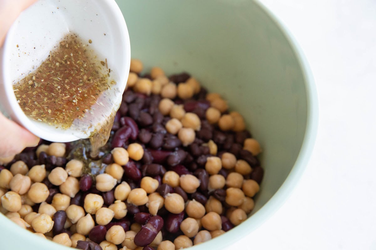 Pouring vinaigrette into the bowl with the beans