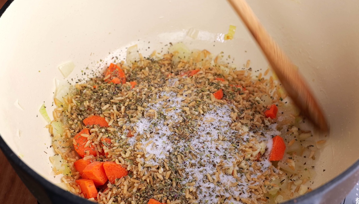 Vegetables, rice, and seasonings in a large pot to make soup.