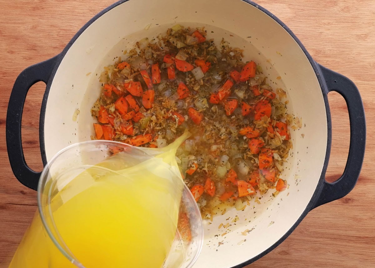 Pouring broth into a pot to make soup.