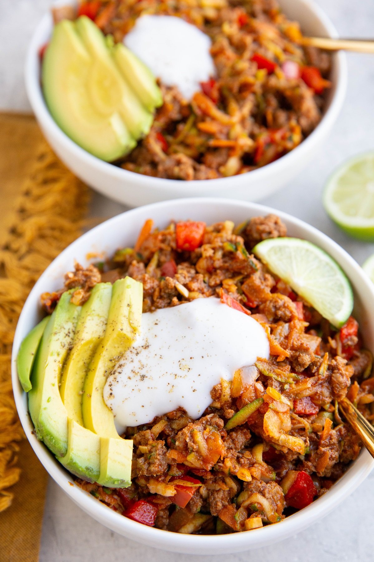 Zucchini and ground beef bowls topped with sour cream and avocado.