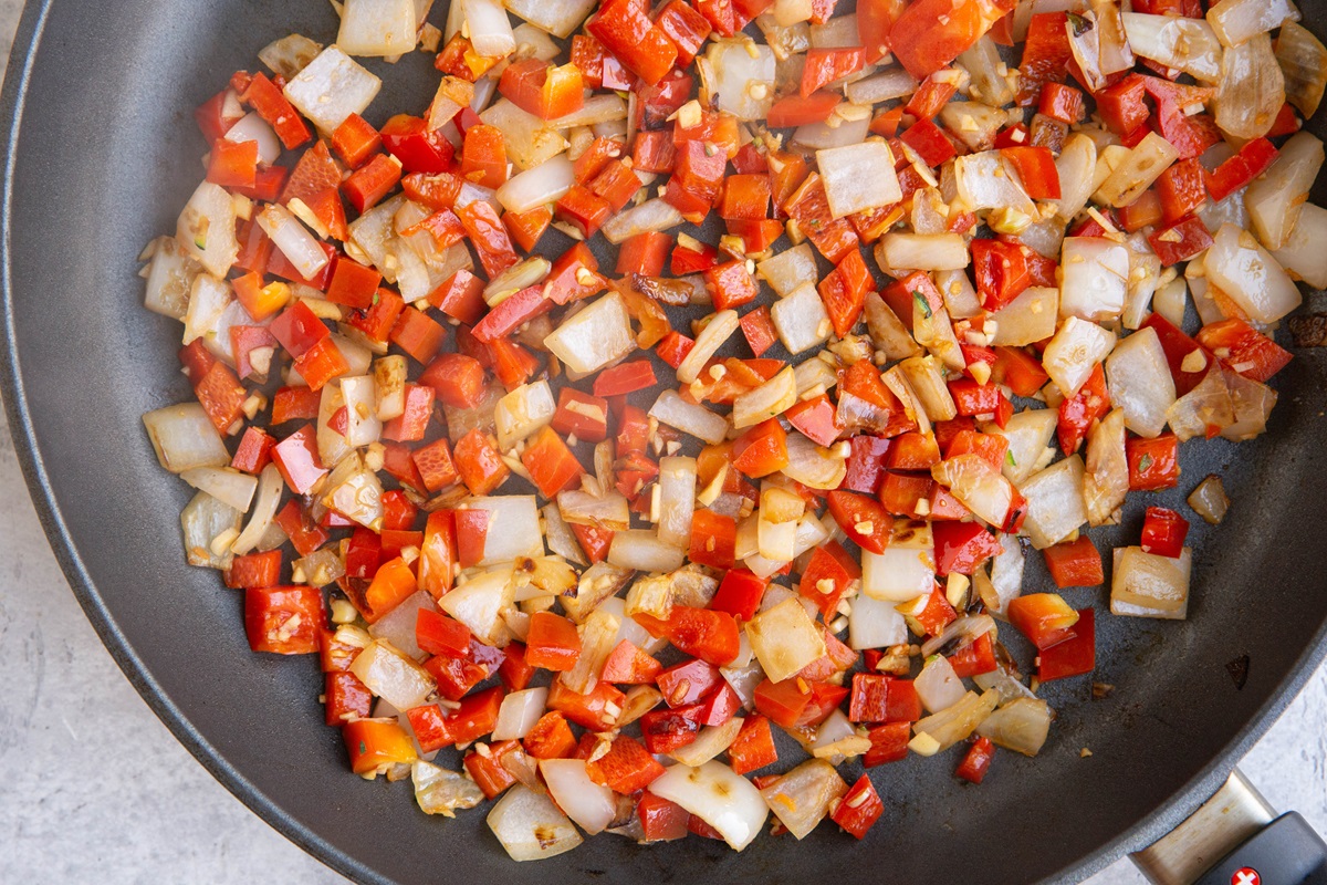 Onion, garlic, and bell pepper cooking in a skillet.