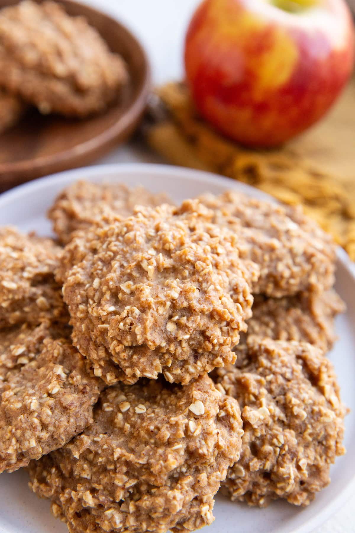 White plate of applesauce cookies with an apple in the background.