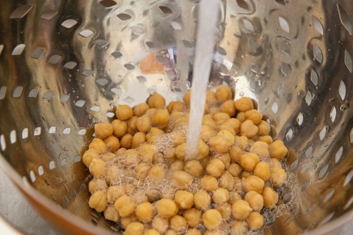 Rinsing chickpeas in a colander with water.