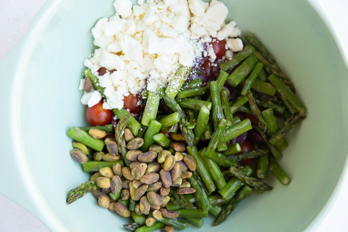 Mixing bowl full of asparagus salad ingredients.