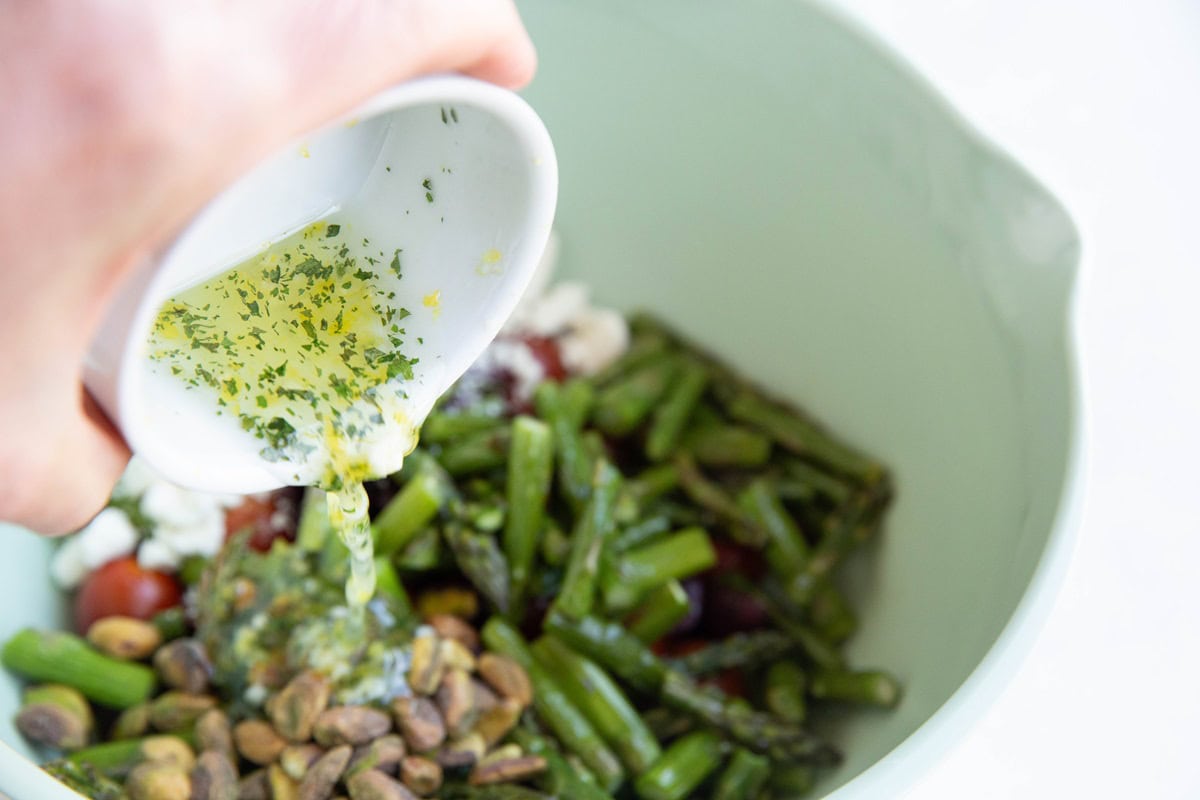 Pouring the lemon vinaigrette into the bowl with the salad ingredients.